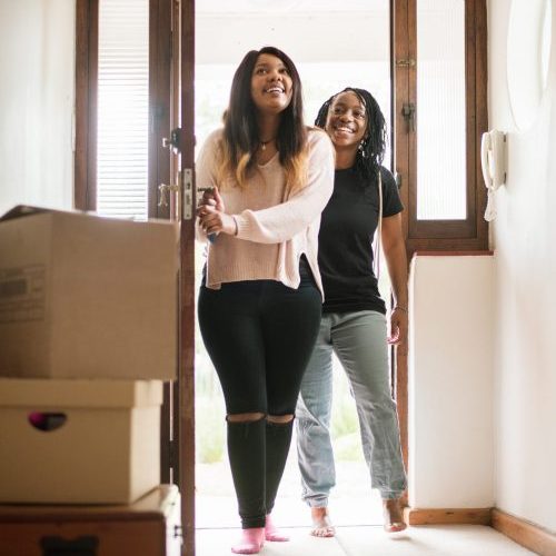 Shot of two young women entering their new home from the main door